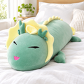 Green little long dragon plushie on a cozy bed